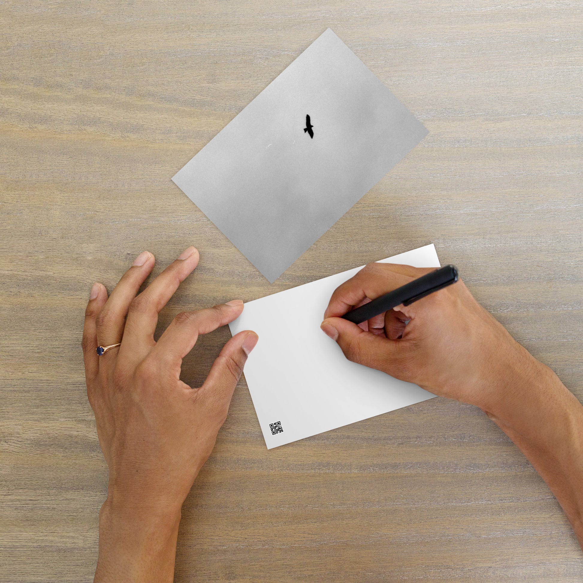 Lifestyle shot of a person holding the 'Bird and Sky (B&W)' postcard, highlighting its thick, high-quality matte paper texture. / 「Bird and Sky (B&W)」ポストカード：手に馴染む厚手のマット紙を使用したポストカード。大切な人へのメッセージカードとしてはもちろん、ミニ・アートとしても楽しめます。